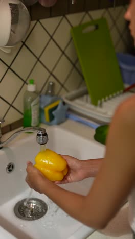 washing yellow pepper in the kitchen sink