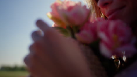 Portrait-of-beautiful-woman-smelling-gentle-flower-bouquet-in-sun-reflection.