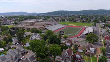 aerial flyover bethlehem city in pennsylvania with traffic on streets. liberty high school and basd stadium in distance. sunny day in summer. wide shot