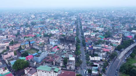 siliguri densely populated cityscape under hazy sky due to air pollution on the banks of mahananda and teesta river in the foothills of himalayas, hill cart road traffic movement, drone view