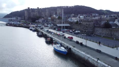 picturesque welsh conwy castle and harbour fishing town boats on coastal waterfront aerial forward left low angle