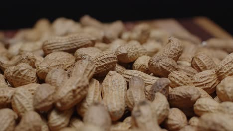 Spinning-pile-of-peanuts-on-cutting-board-close-up-with-black-background