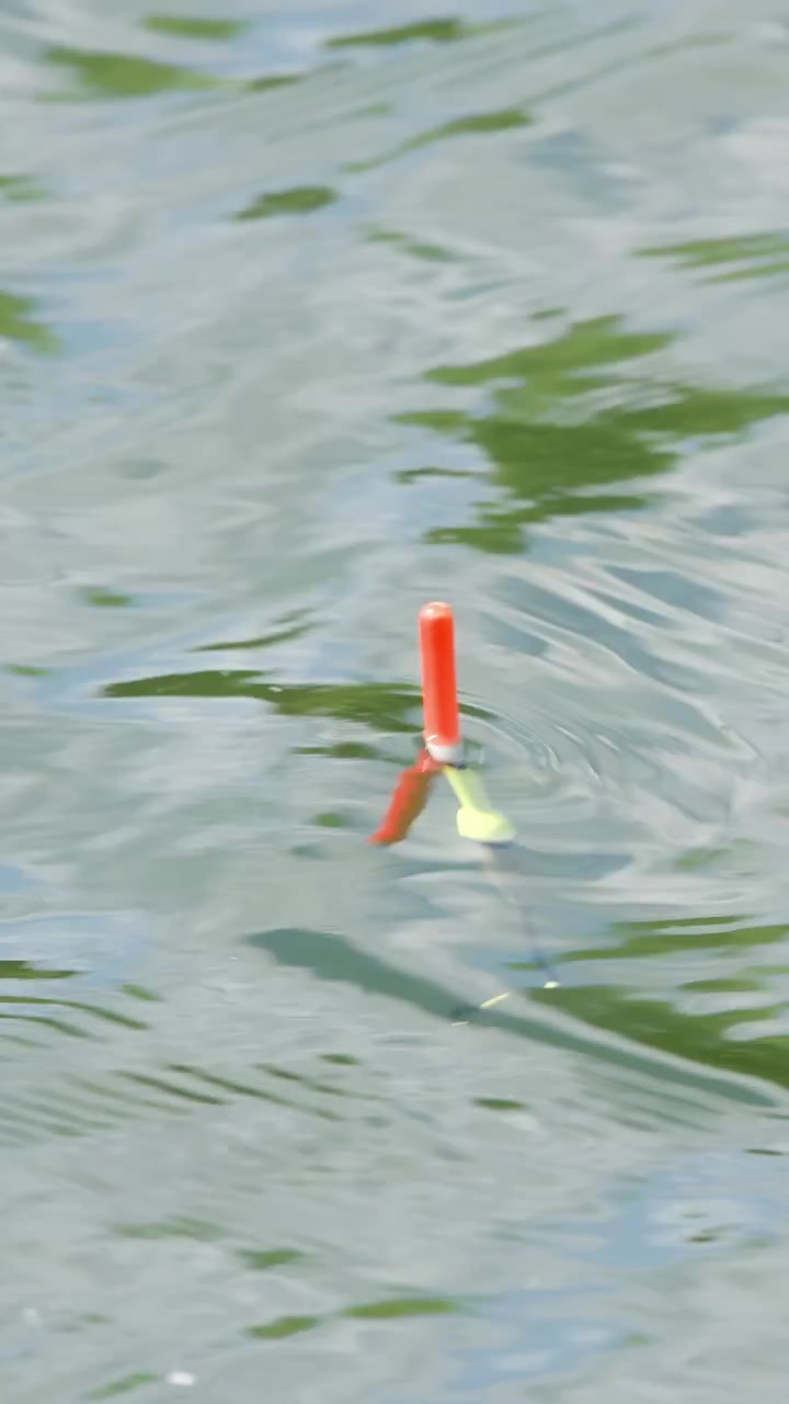 Red and Yellow Fishing Float Bobbing Gently on Calm Water