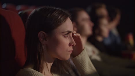 concentrated girl watching thrilling movie at cinema. enjoy cinema concept