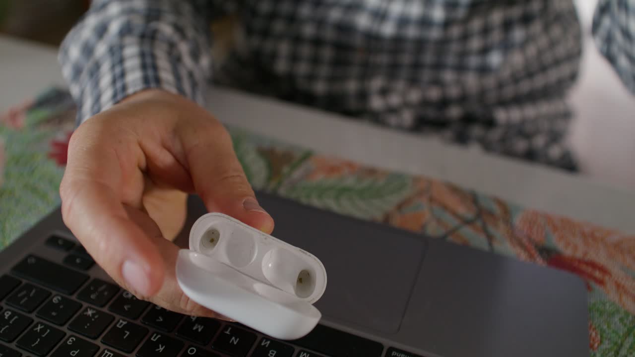 persona con auriculares inalámbricos y un control remoto en una computadora portátil