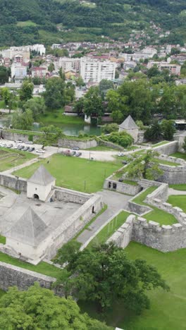 drone shows medieval kastel fortress in banja luka with stone walls and green landscape below, aerial establishing vertical