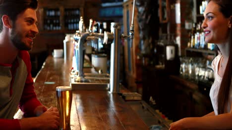 Barmaid-interacting-with-male-costumer-while-serving-beer