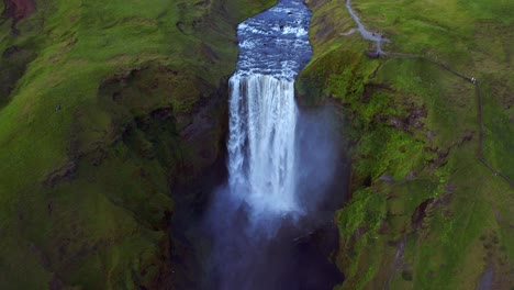 aerial of skogafoss waterfall flowing from towering cliff situated on skoga river in south of iceland