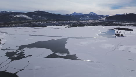 downtown frisco toward keystone colorado aerial cinematic drone lake dillon marina summit cove cloudy snowy winter morning view silverthorne ten mile range breckenridge calm unfrozen ice backwards up