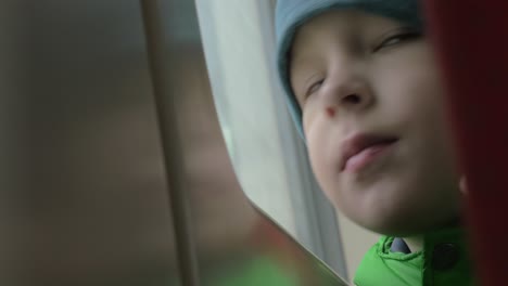 close up view of small boy bored face in winter hat on his place in the rail train