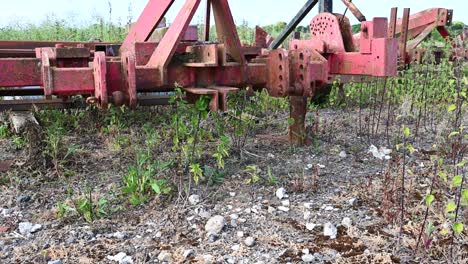 old farm equipment overgrown and lying abandoned in a field rising shot