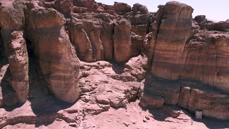 Aerial-slow-and-calming-backward-drone-shot-of-a-sculptured-like-ridge-in-the-middle-of-a-desert,-surrounded-by-sand-and-dirt