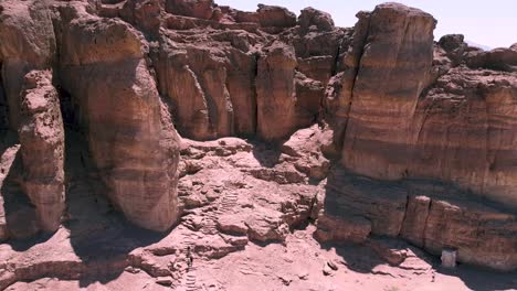 toma aérea lenta y calmante de un dron hacia atrás de una cresta esculpida en medio de un desierto, rodeada de arena y suciedad