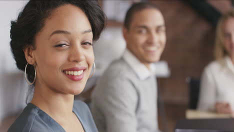 Portrait-of-a-confident-young-hispanic-business-woman-at-boardroom-table-in-trendy-modern-shared-office-space-a-diverse-team-slow-motion-turning-around-smiling