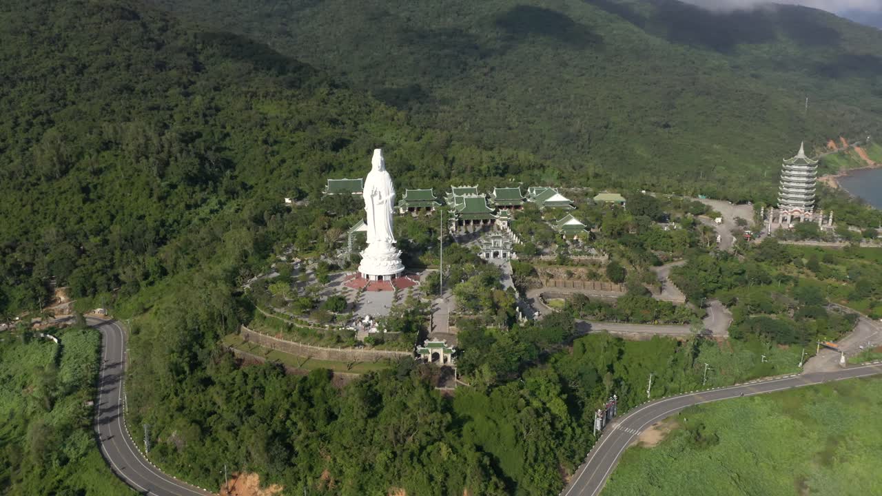 antena dando vueltas alrededor de la estatua alta de buda y la torre del templo con enormes montañas, una costa impresionante y el océano en da nang, vietnam
