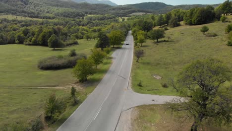 Aerial-drone-shot-over-extra-urban-road-and-car-drive-uphill