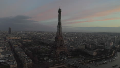 Fly-around-famous-tourist-attraction,-Eiffel-Tower-against-twilight-sky.-City-at-dusk.-Paris,-France