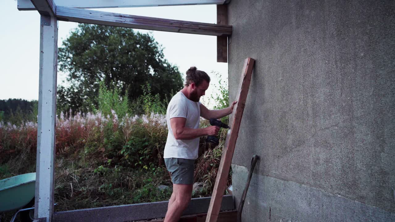 노르웨이 의 인드레 포센 에서 온실 을 짓기 위해 나무 에 구 ⁇  을  ⁇ 는 사람 - 정적 촬영