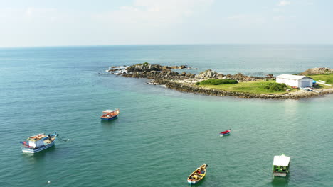 fisherboats anchored at a turquoise colored water coast, praia armacao, florianopolis, santa catarina, brazil