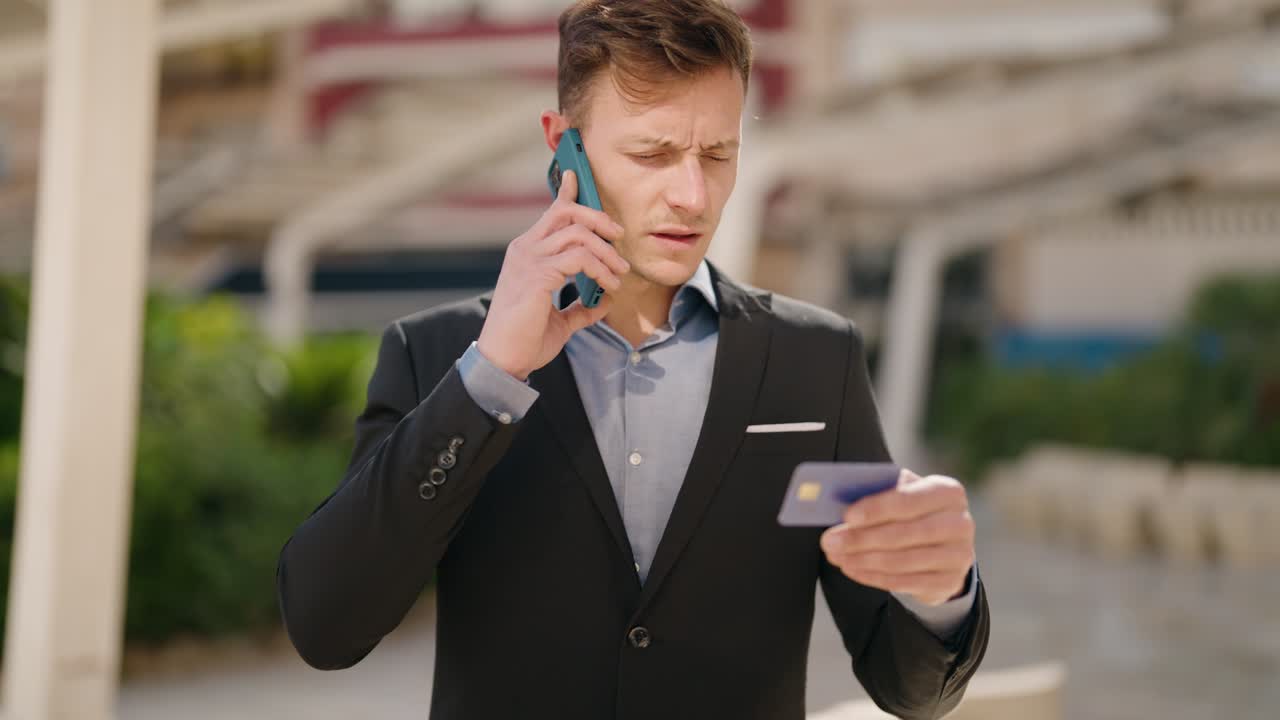 joven caucásico hablando en el teléfono inteligente usando tarjeta de crédito en la calle