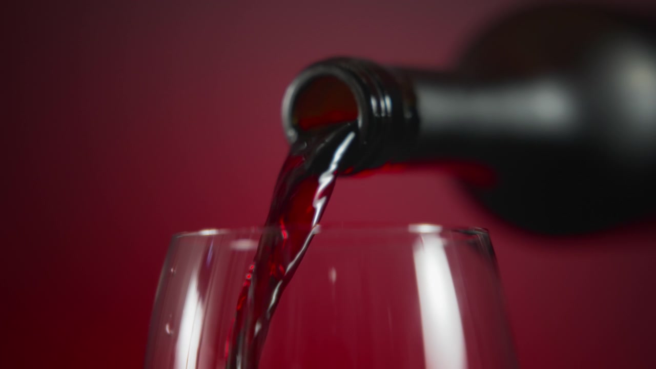 Bottiglia che versa vino rosso in un calice.