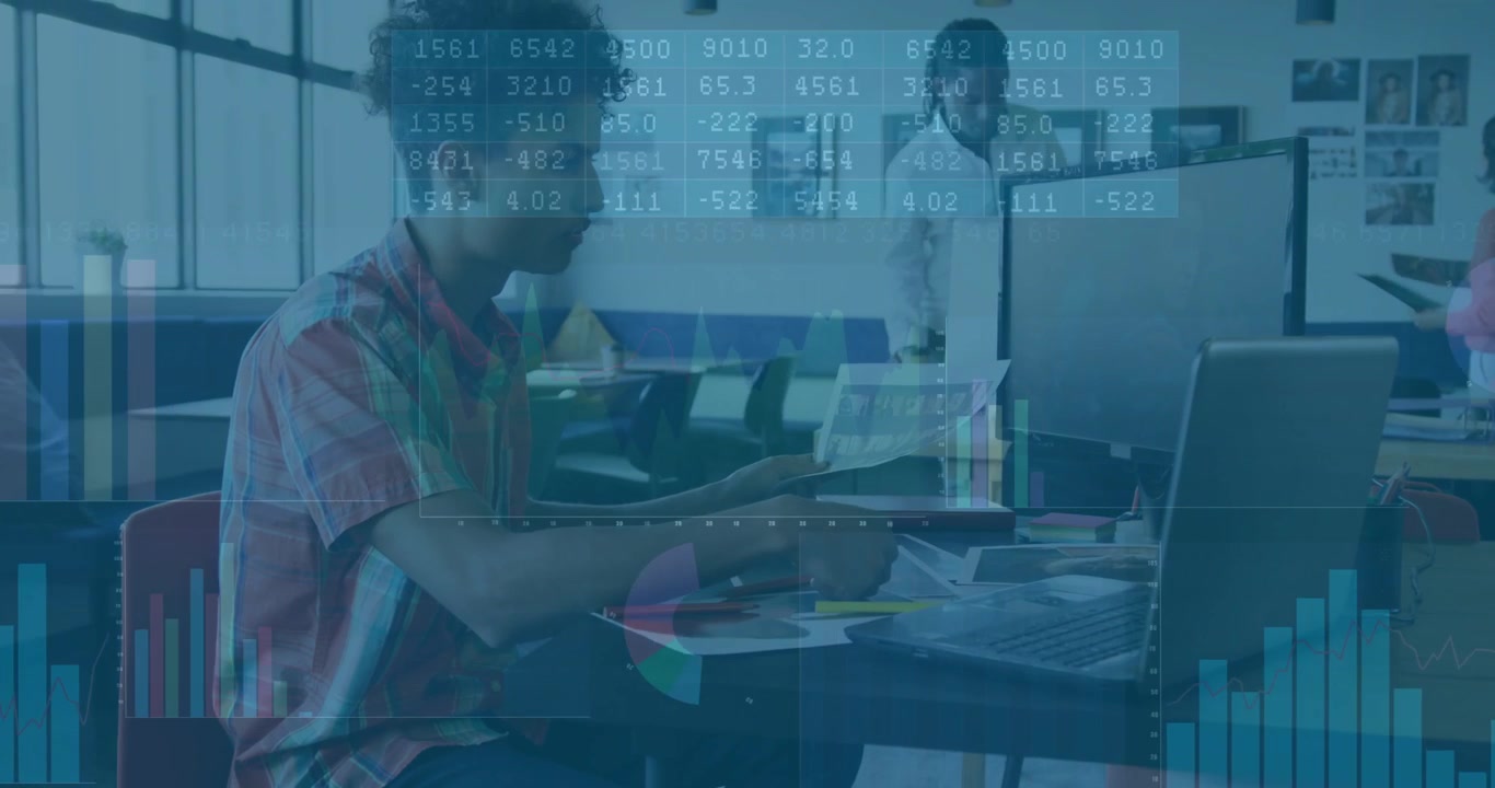 Young Man Analyzing Financial Data on Laptop in Modern Office