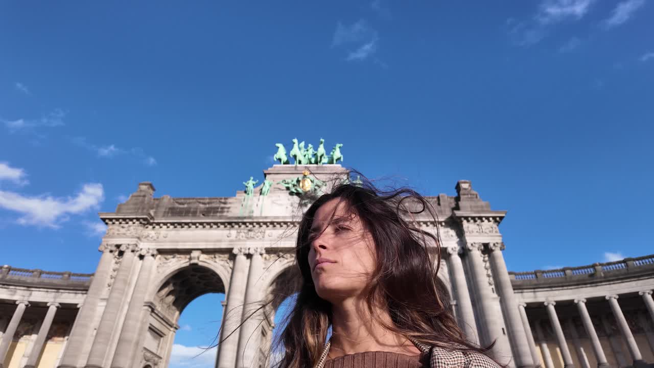 Slow motion of a confident woman standing before Cinquantenaire Arch in Brussels