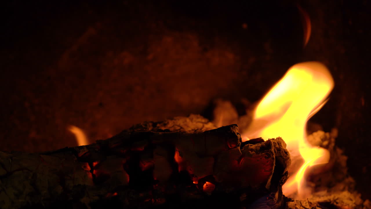 An out of focus flaming log coming into focus with beautiful yellow orange flames.