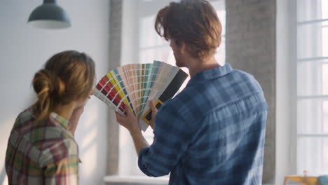 una pareja feliz usando la paleta de colores en una casa nueva. una familia discutiendo el diseño en el interior.