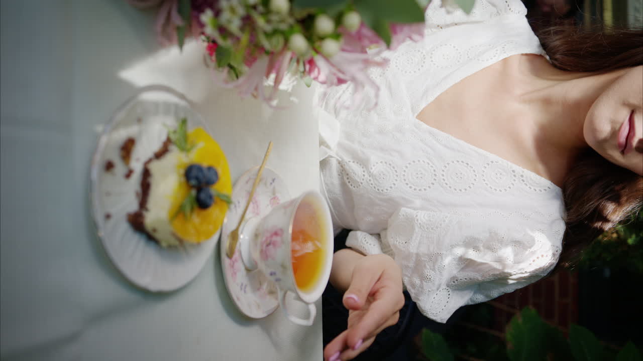 Woman drinking black tea, composition with flowers, macaroons sweets desert and coffee and tea