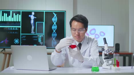 young asian male research scientist holding glass test-tube and looking