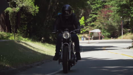 Slow-Motion-of-Motorcyclist-With-Leather-Jacket-Riding-on-a-Wooded-Road