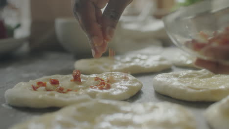 preparing small flatbreads with toppings
