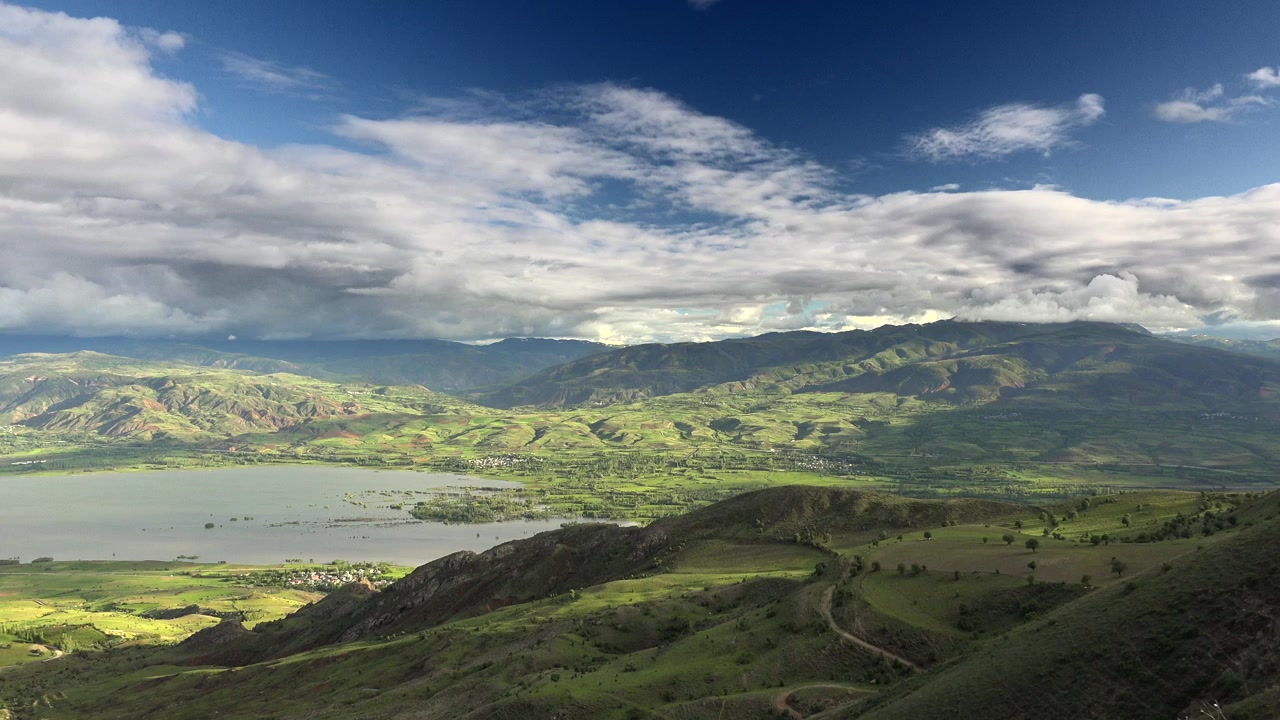 Vista panoramica di una lussureggiante valle verde e un lago sotto un cielo nuvoloso