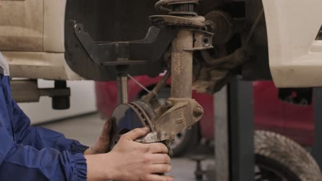 car mechanic replacing car wheel brake shoes of lifted automobile at repair service station