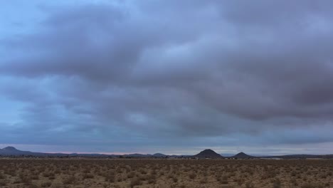 the mojave desert landscape at sunrise or sunset on an overcast day - sliding aerial view of the rugged terrain