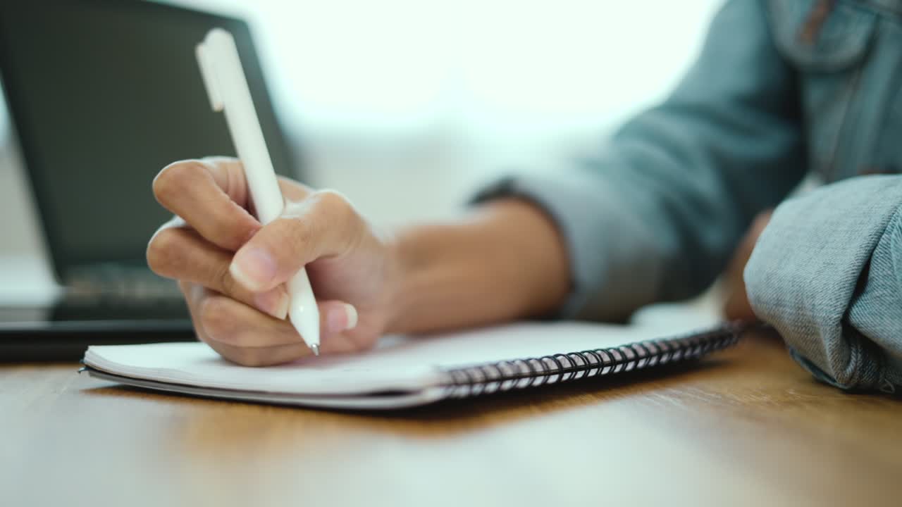 close-up mano creador mujer tomar notas su idea en casa. mujer de negocios con bolígrafos y papeles en la mesa. estudiante haciendo la tarea después de estudiar en línea.
