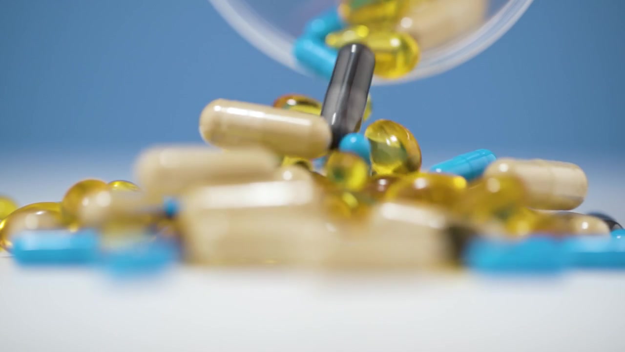 Una serie di compresse e capsule colorate si riversa drammaticamente su una superficie bianca al rallentatore in 4K. Lo sfondo blu vibrante enfatizza il movimento caotico, creando uno scenario mozzafiato.