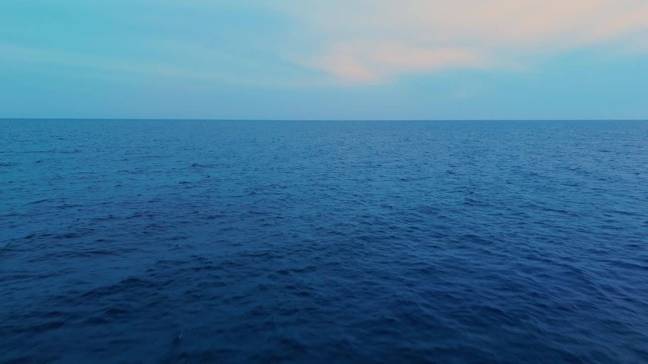 Calm blue ocean at sunset with soft pastel skies, a peaceful and soothing scene