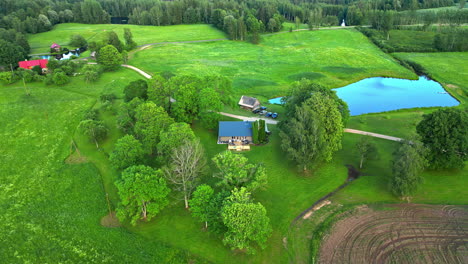 Green-meadow,-private-estate-and-water-pond,-aerial-drone-view