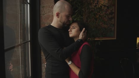 couple hugging by a window