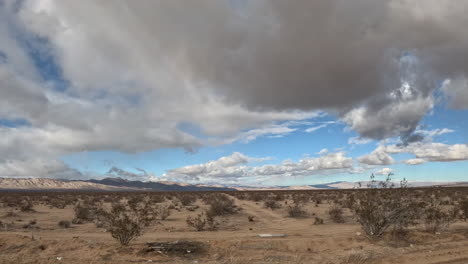 the mojave desert landscape passes by as clouds cross the sky in the driving hyper lapse from the point of view of a car passenger