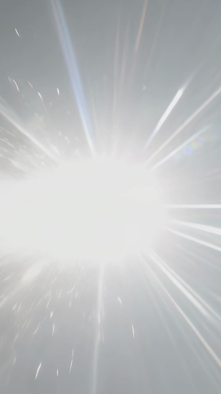 Vertical video: Rising exposure, central light flooding frame with lens flare, left sparks