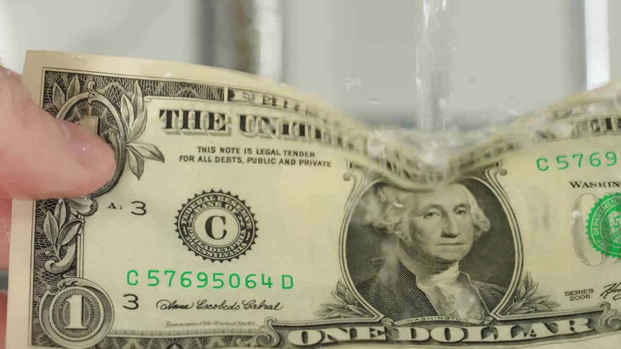 Washing dollar under water, slow motion.