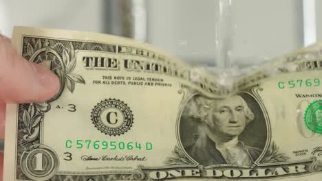 washing dollar under water, slow motion.