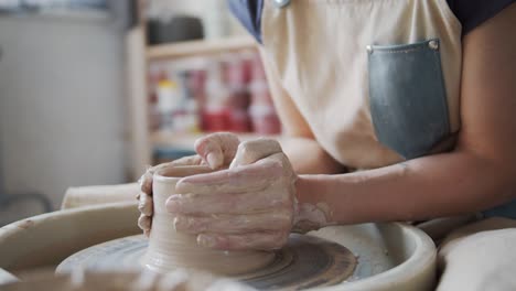 female potter makes a pot on the pottery wheel.