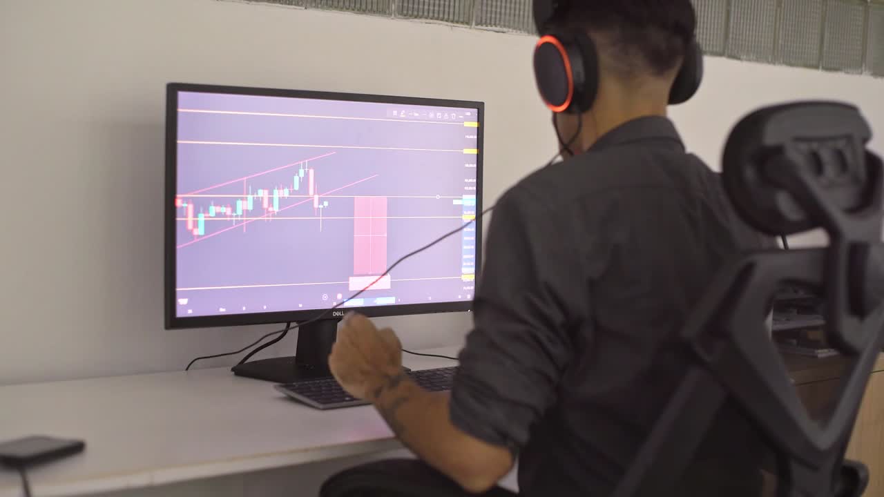 Trader di borsa che analizza dati finanziari su un monitor del computer, indossando cuffie LED cangianti, mostrando intensa concentrazione durante la ricerca di mercato
