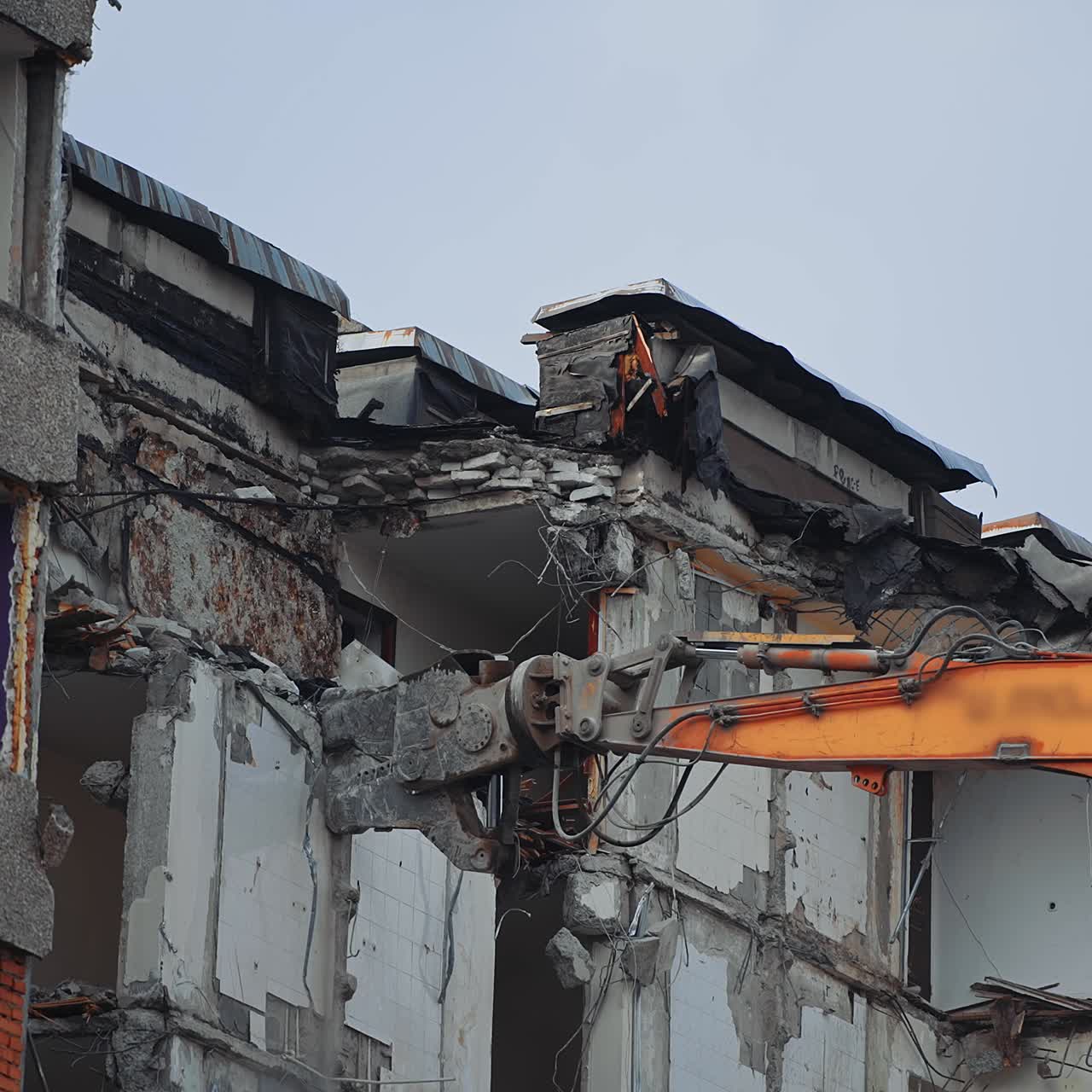 Breaking off the walls of the building with the help of demolishing machinery. Dismantling the building ruined by the natural disaster