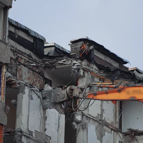breaking off the walls of the building with the help of demolishing machinery. dismantling the building ruined by the natural disaster