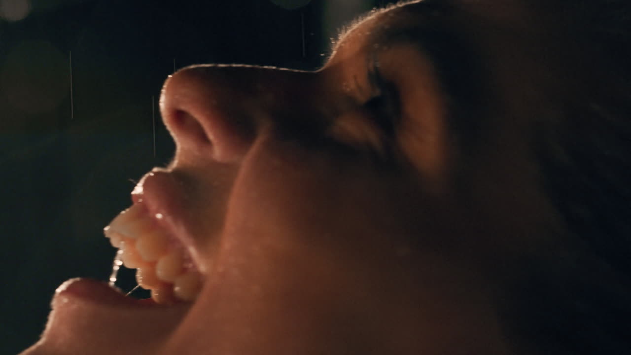 retrato de cerca de una hermosa mujer joven de pie bajo la lluvia disfrutando de las suaves gotas de lluvia tocando la piel emociones calmantes en cámara lenta